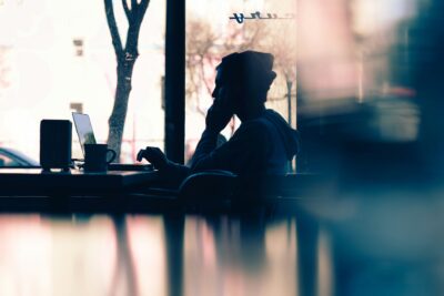blurred abstract image of person sat at a laptop