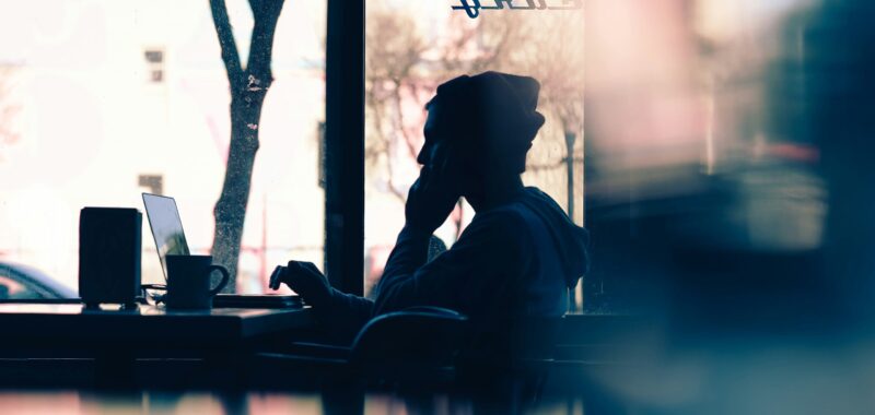 blurred abstract image of person sat at a laptop