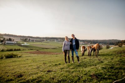 Two people on an open field surrounded by cows
